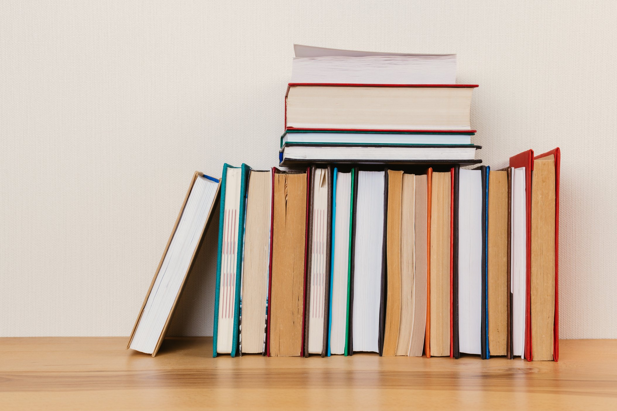 Simple composition of many hardcover books, raw of books on a wooden table and a light background. I'm going back to school. Copy space Education.